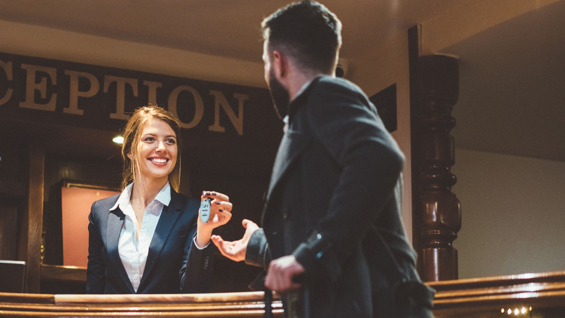 Image of a hotel receptionist handing over a key to a guest