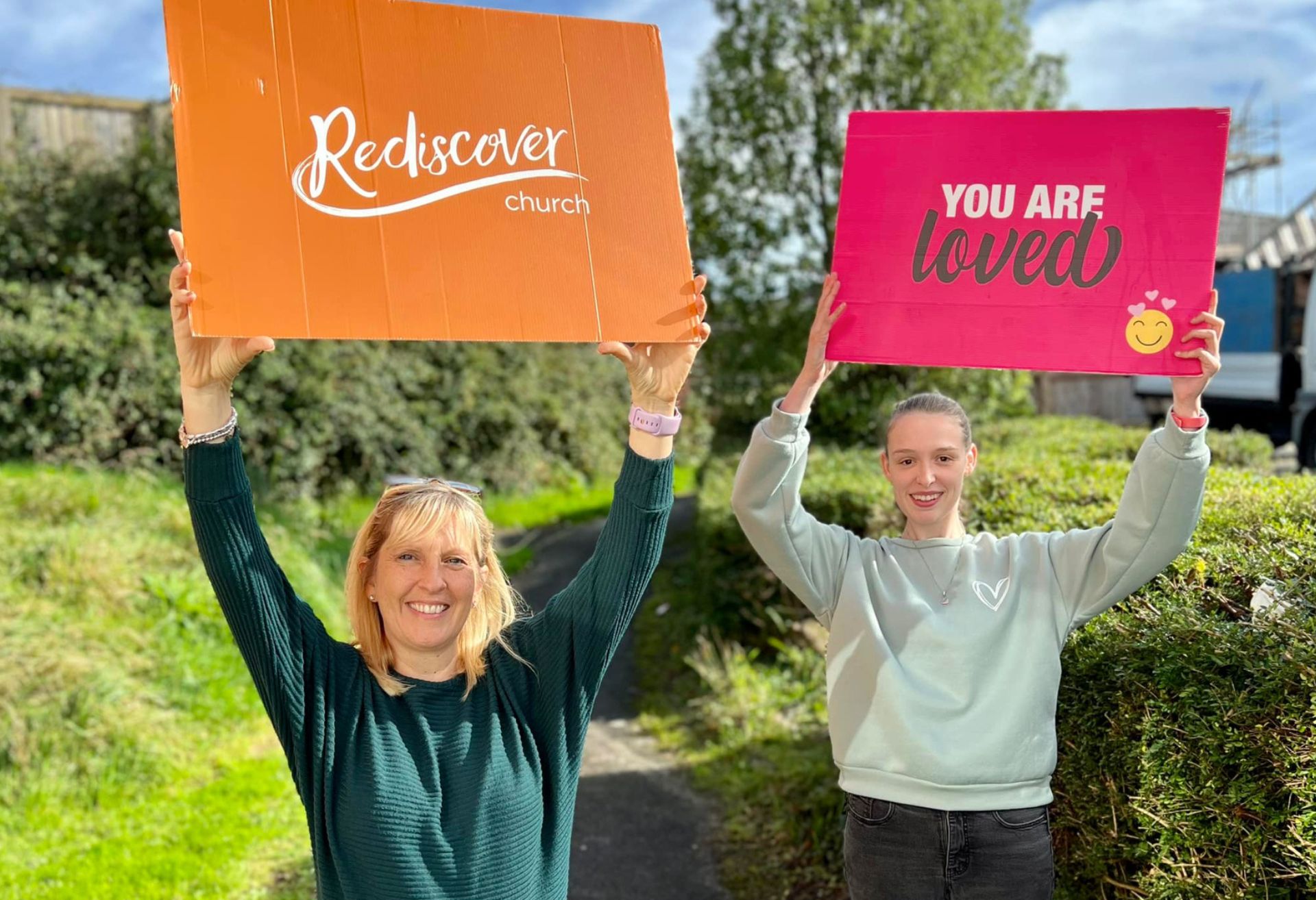 Two people holding placards for Rediscover Church